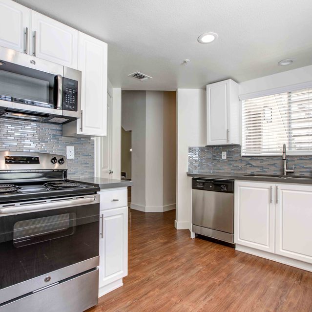 Stoneridge – Bright modern kitchen with white cabinetry and stainless-steel appliances, complemented by dark countertops