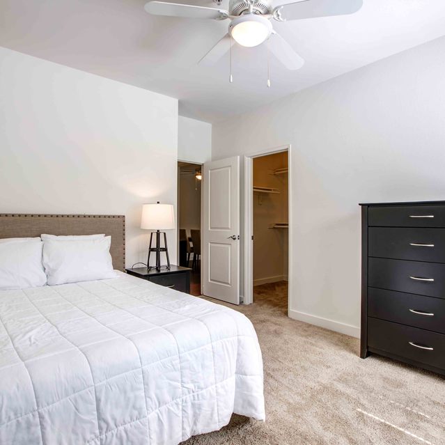 Stoneridge – Cozy bedroom with a neatly made bed featuring a white comforter and upholstered headboard