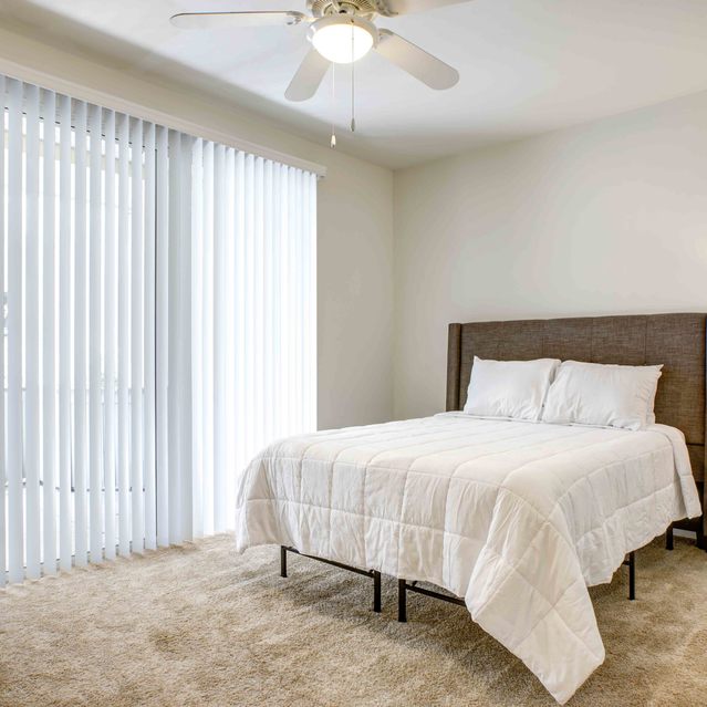 Stoneridge – Bright bedroom with a neatly made bed featuring a white comforter and upholstered headboard