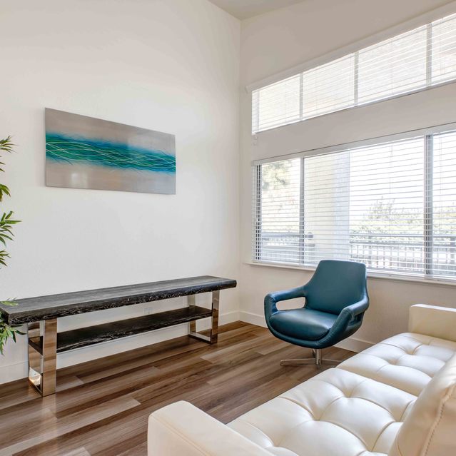Stoneridge – Bright sitting area with a cream tufted sofa and a modern blue accent chair on warm wood flooring