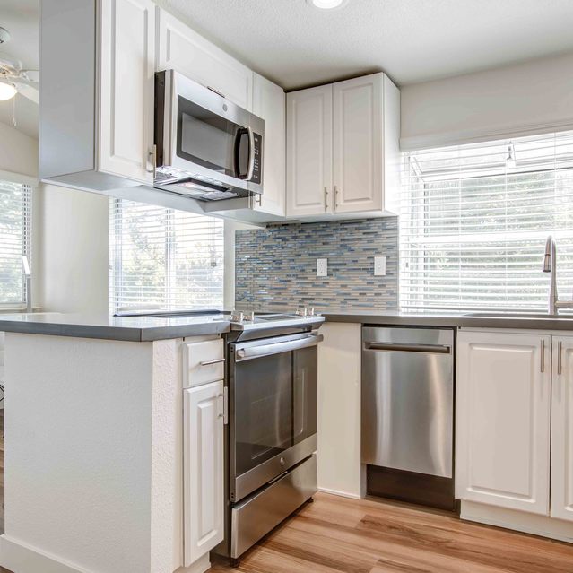 Stoneridge – Modern kitchen with white cabinetry, stainless steel appliances including a microwave and oven