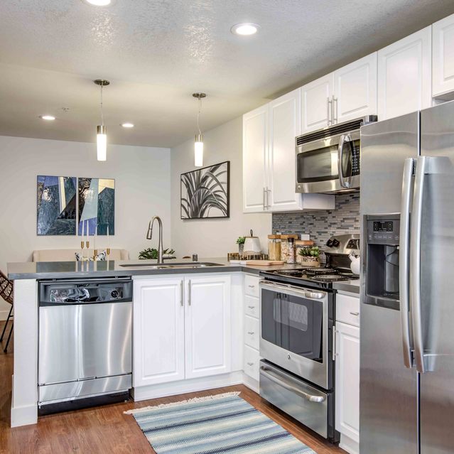 Stoneridge – Contemporary kitchen with white cabinetry and stainless-steel appliances, including a double-door refrigerator