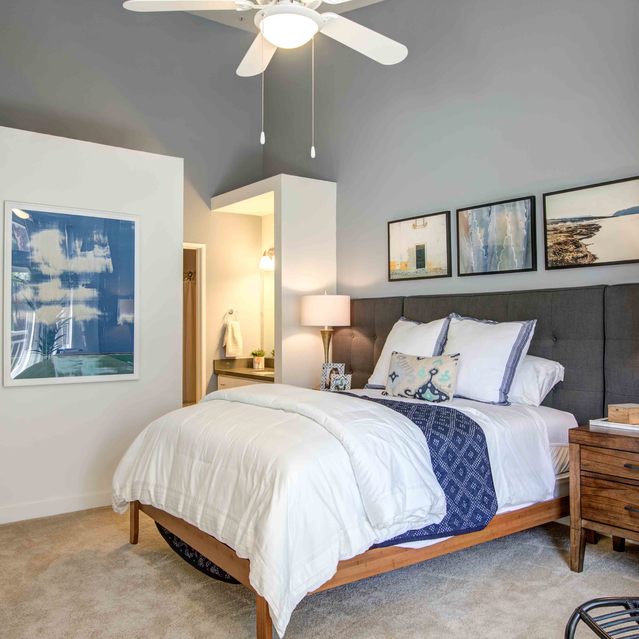 Stoneridge – Stylish bedroom with a dark upholstered headboard and layered white and navy bedding